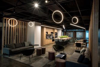 office seating stools and couch with kitchen in background, long raised centre table and circle lights