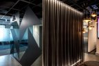 Office interior design of curtain against wall with lights for effect and adjoining wall with black reflective shapes and matt shapes