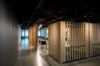 Office with vertical wooden spaced slats to separate booths and casual meeting area. Polished concrete flooring and exposed ceilings