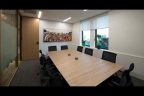 Business Meeting Room with long rectangular light wood table, white walls and wall art on back wall.