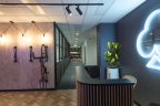 Brand new office fitout reception area with parquetry flooring, illuminated logo in background on gray wall, wooden slat reception with black accents and bike hanging rack. Looks through to hallway with multiple offices.