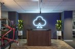 newly designed office for Goeasy showing wooden front reception desk with black top, luminated logo on back grey wall, white planters either side and red bike hanging on left.