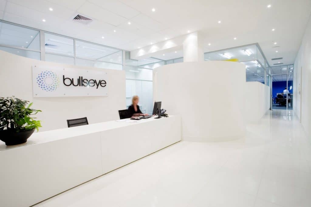 The use of white and downlights to highlight a blue and black logo and blue feature wall in meeting room in background for a commercial interior design melbourne